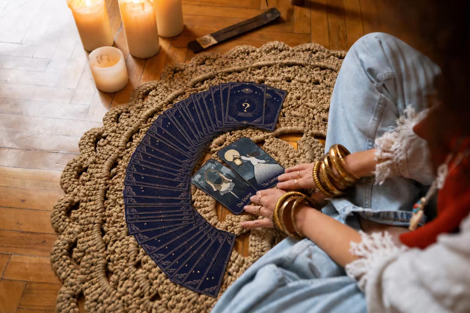A person sitting on a rug drawing oracle cards by candlelight